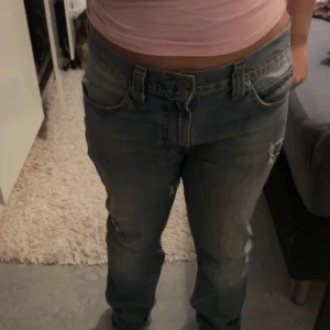 Levis 511 blå jeans - Klassiska blå Levis 511 jeans med rak passform och låg midja. Jeansen har fem fickor, knappgylf och diskreta slitningar för en avslappnad look. Perfekta för dig som gillar tidlös denimstil.