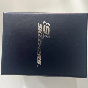 Svart klocka från Skechers - Stilren svart klocka från Skechers med rund urtavla och svart armband. Levereras i originalförpackning med Skechers-logga. Perfekt accessoar för en modern look.