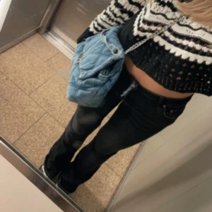 Svarta lågmidjade bootcut jeans - Säljer ett par svarta bootcut jeans med normal passform. Klassisk femficksmodell och knappgylf. Perfekta till vardagslooken och lätta att matcha med olika toppar. 