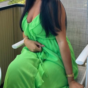 Grön långklänning med volang och knyt - Säljer en snygg långklänning i klargrönt med smala axelband och volangdetaljer framtill. Klänningen har knyt vid bysten och är tillverkad i ett lätt, flowy material som passar perfekt till sommaren.