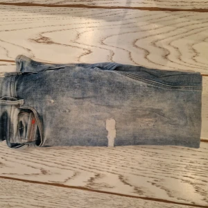 Ljusblå skinny jeans från Diesel Sleenker - Säljer ett par ljusblå skinny jeans från Diesel, modell Sleenker. Jeansen har slitna detaljer och klassisk femficksdesign. Perfekta för dig som gillar en tight passform och en trendig, avslappnad look.