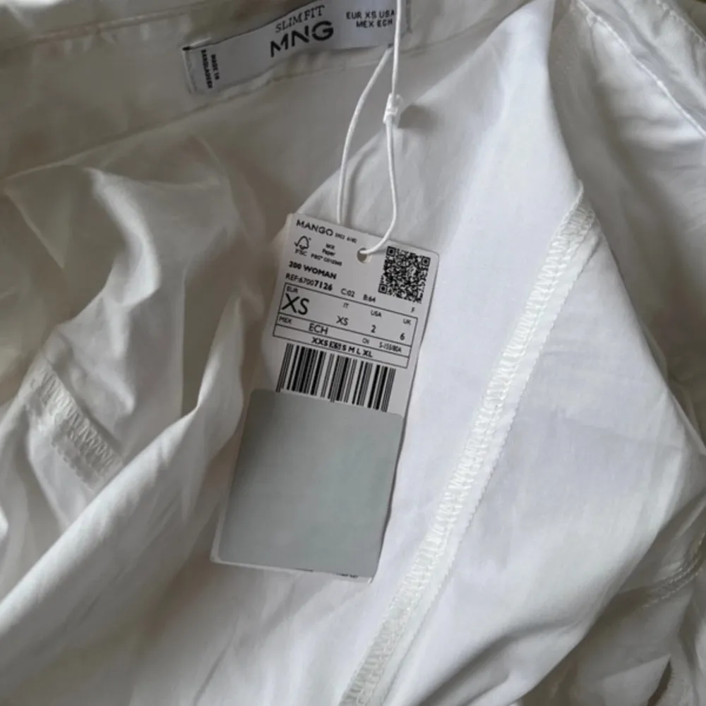 Säljer en vit slim fit skjorta från Mango i storlek XS. Skjortan har dragkedja framtill och på ärmarna, vilket ger en modern och edgy look. Tillverkad i bomull och passar perfekt till dig som gillar stilrena plagg med en twist. Helt oanvänd med prislapp kvar. Paidat.