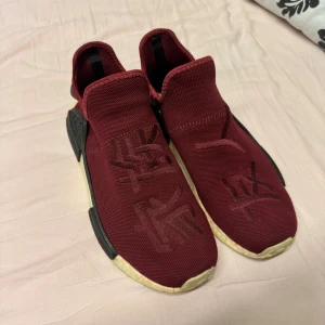 Human race friends and family - Adidas human race friends and family Snygga vinröda sneakers från Adidas med en unik design och text på ovansidan. Skorna har en bekväm sula och elastisk passform. Storlek 43,5-44