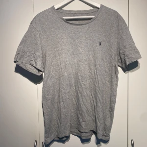 Polo Ralph Lauren Grå T-shirt  - Polo Ralph Laurent klassisk grå t-shirt med liten broderad logga på bröstet. Perfekt basplagg till garderoben. Sparsamt använd och i fint skick. Storlek L men passar M. Nypris 900kr. Fler bilder kan fås i DM. 