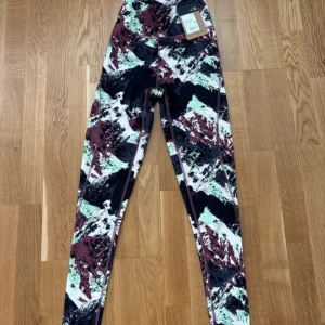 Mönstrade träningstights från The North Face - Säljer ett par färgglada träningstights från The North Face i storlek XS. Tightsen har ett abstrakt mönster i svart, vinrött, grönt och vitt samt hög midja och logga på benet. Perfekta för gymmet eller löprundan.
