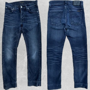 Svarta Nudie Jeans  - Säljer nu dessa riktigt snygga Nudie Jeansen som har fått en riktigt snygg tvätt med tiden. Storlek 29/32 på etikett men är uppsydda professionellt till 29/30. Modell Tilted Tor sitter Slim Fit. Bra skick inga hål eller liknande. Hör av dig om du undrar något eller vill ha fler bilder. Pris är diskuterbart vid snabb och smidig affär. Total 100cm Från skrevet 73cm Midja 38cm