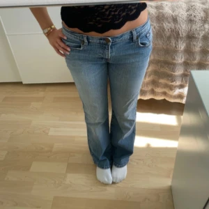 Blå bootcut jeans - Snygga blå bootcut jeans med låg midja. Perfekta för en avslappnad stil. Klassisk design med fem fickor och knappgylf.