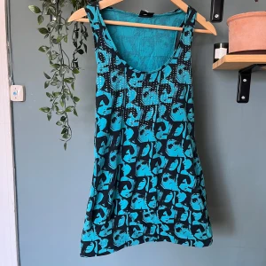 Turkos och svart mönstrad linnetopp/klännig - Säljer en cool turkos och svart linnetopp som också går att använda som mini klännig då den är lite längre, med ett unikt mönster. Perfekt för våren! Skriv vid frågor🤗