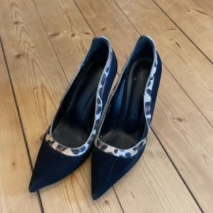 Svarta pumps med leopardmönster - Snygga svarta pumps med spetsig tå och klack. De har en trendig leopardmönstrad kant som ger en extra touch. 