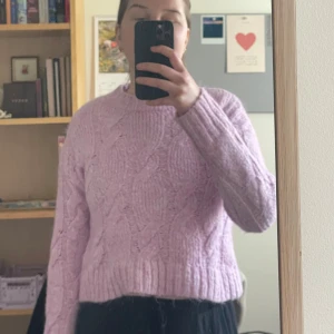 Rosa stickad tröja - Mysig ljuslila stickad tröja med kabelstickat mönster och croppad passform. 