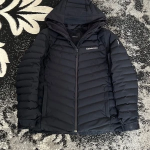 Skidjacka Peak Performance - Skidjacka inte en vanlig från peak performance. Kostar runt 3,5-5k , ny mitt pris 1750. Perfekt för skidsäsongen eller som vinterjacka.                                                     90% dun och 10% fjäder (700 fillpower) Vindtät och vattenavvisande Fast, justerbar huva Fast snölås i midjan Sidofickor, liftkortsficka på ärmen och en innerficka - alla med dragkedja