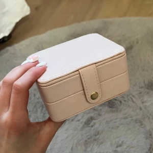 Ljusrosa smyckesväska med spegel - Säljer ett litet och smidigt ljusrosa smyckeskrin med spegel på insidan av locket. Skrinet har flera fack för ringar och smycken samt stängs med en tryckknapp i guld. Perfekt att ha med på resan eller för att organisera smycken hemma. 😍kostade 300 kr när jag köpte det. Säljer för halva priset 😍