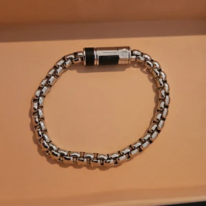 Oanvänt silverfärgat armband från Louis Vuitton - Säljer ett stilrent armband från Louis Vuitton i silverfärg med robust kedjedesign och svart detalj vid låset. Perfekt accessoar för att lyfta din outfit med en exklusiv touch. Armbandet var en studentpresent till vår son som tyvärr inte ville ha det och därför har det blivit liggande. Nypris 4550kr.