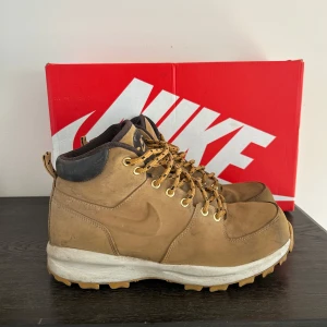 Kängor från Nike - Säljer ett par robusta bruna kängor från Nike med snörning och grov sula. Perfekta för utomhusaktiviteter med en bekväm passform och slitstarkt material. Kängorna har en diskret Nike-logga på sidan och är designade för att klara tuffa förhållanden. Knappr använda och har mycket kvar o ge. Box följer med