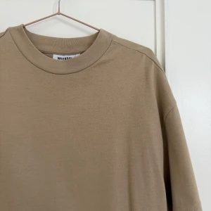Beige t-shirt från Weekday - Säljer en stilren beige t-shirt från Weekday. Den är tillverkad i 100% bomull. Overdized
