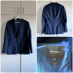 Mörkblå kostym från Dressmann - Snygg mörkblå kostym från Dressmann i slim fit. Den är i bra skick. Kavajen är storlek 46R i slim fit och byxorna är 30/32 i slim fit