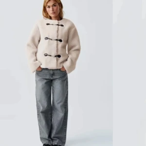 Beige teddyjacka med knappar - Mysig beige teddyjacka med svarta knappar framtill. Jackan har en avslappnad passform och långa ärmar, perfekt för kyligare dagar. Den fluffiga texturen ger en trendig look. Storlek xs, om någon vill byta mot en i storlek M går det bra
