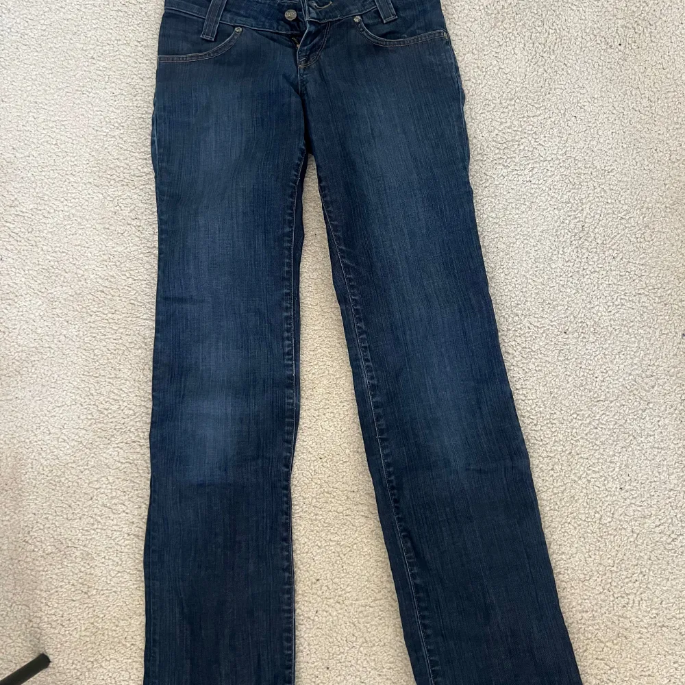 Snygga blå jeans från Lee med klassisk femficksdesign. De har en normal passform och är perfekta för en avslappnad stil. Jeansen har en knappgylf och är tillverkade i slitstarkt denim.. Farkut & Housut.