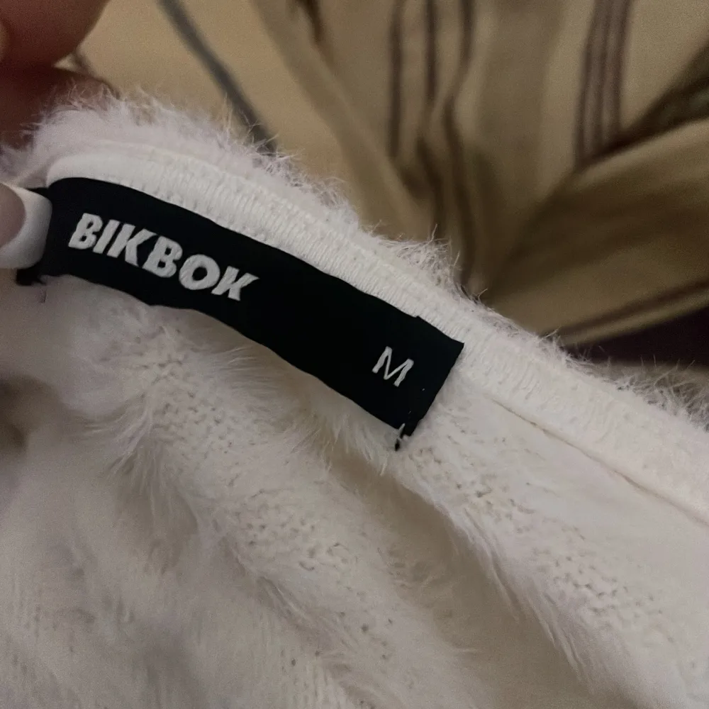 Säljer en supermjuk och fluffig vit topp från BikBok. Den har en tight passform och korta ärmar, perfekt för en mysig look. Toppen är gjord i ett syntetmaterial som ger en härlig känsla. Perfekt för att hålla sig stilren och bekväm.. Yläosat.