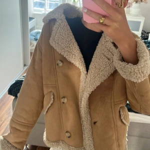 Beige jacka med teddyfoder från Zara - Säljer en snygg beige jacka från Zara med mysigt teddyfoder. Jackan har knappar framtill och två fickor. Kan användas både vinter och höst/vår. Storlek 164 men passar mig som är 172 storlek S/XS.