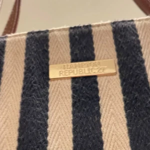 Snygg och somrig vintage retro väska från Hampton Republic 27 blå-vitrandig - Stor handväska/ axelväska från Hampton Republic 27. Knappt använd så i mycket bra skick. Perfekt nu när sommarsäsongen snart är här och man vill ha med sig badkläder tex😉 En vintage/ retro väska men hel och ren både på in- och utsidan.  Mått; Längd; 40cm Höjd; 36cm Bredd; 10 cm mätt vid väskans botten. Katter finns i hemmet .