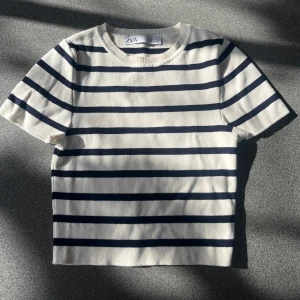 Randig kortärmad tröja från Zara - Säljer en fin randig tröja från Zara i marinblått och vitt. Tröjan har korta ärmar och en rund halsringning, perfekt nu inför sommaren! 💗Utan defekter