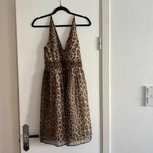 Leopardmönstrad klänning från Vero Moda - Snygg leopardmönstrad klänning från Vero Moda med djup v-ringning och smala axelband. 