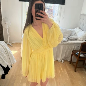 Gul klänning med v-ringning - Säljer en gul klänning med v-ringning och långa ärmar. Klänningen är öppen i ryggen.
