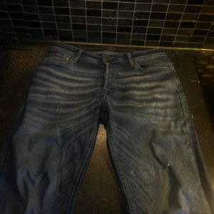 Blå jack n Jones jeansbyxor - Säljer ett par klassiska blå jeansbyxor med en normal passform. Byxorna har en snygg tvättad look och fem fickor. Perfekta för en avslappnad stil. Köpta från jack n Jones, tvär feta! 