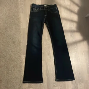 Mörkblå bootcut jeans - Snygga mörkblå bootcut jeans med kontrasterande vita sömmar. Klassisk femficksdesign med dekorativa knappar på bakfickorna. Perfekta för en stilren look. Sköna, nya och låg midja💗