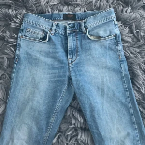 Blå jeans från J.Lindeberg - Snygga blå jeans från J.Lindeberg med en klassisk femficksdesign. Den har ett hål på baksidan men kan lätt gå att sy ihop. 