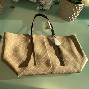 Helt ny Marlene Birger Abo tote  - Snygg beige shoppingväska från Marlene Birger beige . Perfekt för att bära med sig allt man behöver under dagen. Väskan har en rymlig insida och en praktisk innerficka.