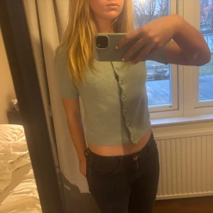 Kortärmad kofta med knappar - Säljer en söt ljusgrön kofta med korta ärmar och knappar framtill. Koftan har en normal passform och är tillverkad i ett mjukt material. Använd fåtal gånger💕