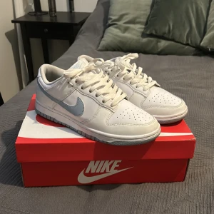 Nike dunks i färgen vit / ljusblå / blå. Storlek 41 - Säljer ett par snygga nike dunk lows i storlek 41. Köpta på mäns avdelningen på nike affären i Stockholm men passar även för tjejer. Använda ett par gånger men ser fortfarande väldigt nya ut.