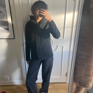 Svart kappa  - Säljer denna svarta kappan med dragkedja. Jackan har en hög krage och långa ärmar, perfekt för kyliga dagar. Den är både stilren och bekväm, idealisk för vardagsbruk. Använt fåtal gånger, kontakta vid frågor 