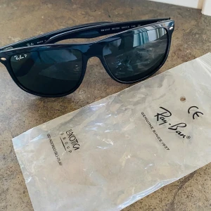 Svarta solglasögon från Ray-Ban - Snygga svarta solglasögon från Ray-Ban med polariserade glas. Tillverkade i Italien, dessa glasögon har en klassisk design med Ray-Ban-loggan på sidan. Perfekta för soliga dagar och ger ett stilrent intryck. Helt nya, använda fåtal gånger. Saknar fodral. 