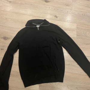 Svart tröja med dragkedja - Säljer en stilren svart tröja med dragkedja vid halsen. Tröjan har långa ärmar och en enkel design som passar till många tillfällen. Perfekt för en avslappnad look.