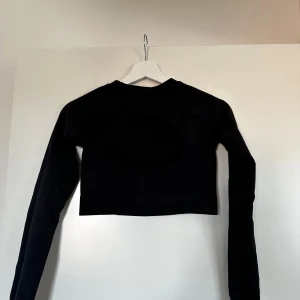 Svart träningstopp - Snygg svart croppad träningstopp med lång ärm och en öppen ryggdetalj. Stretchigt material och väldigt bekväm!