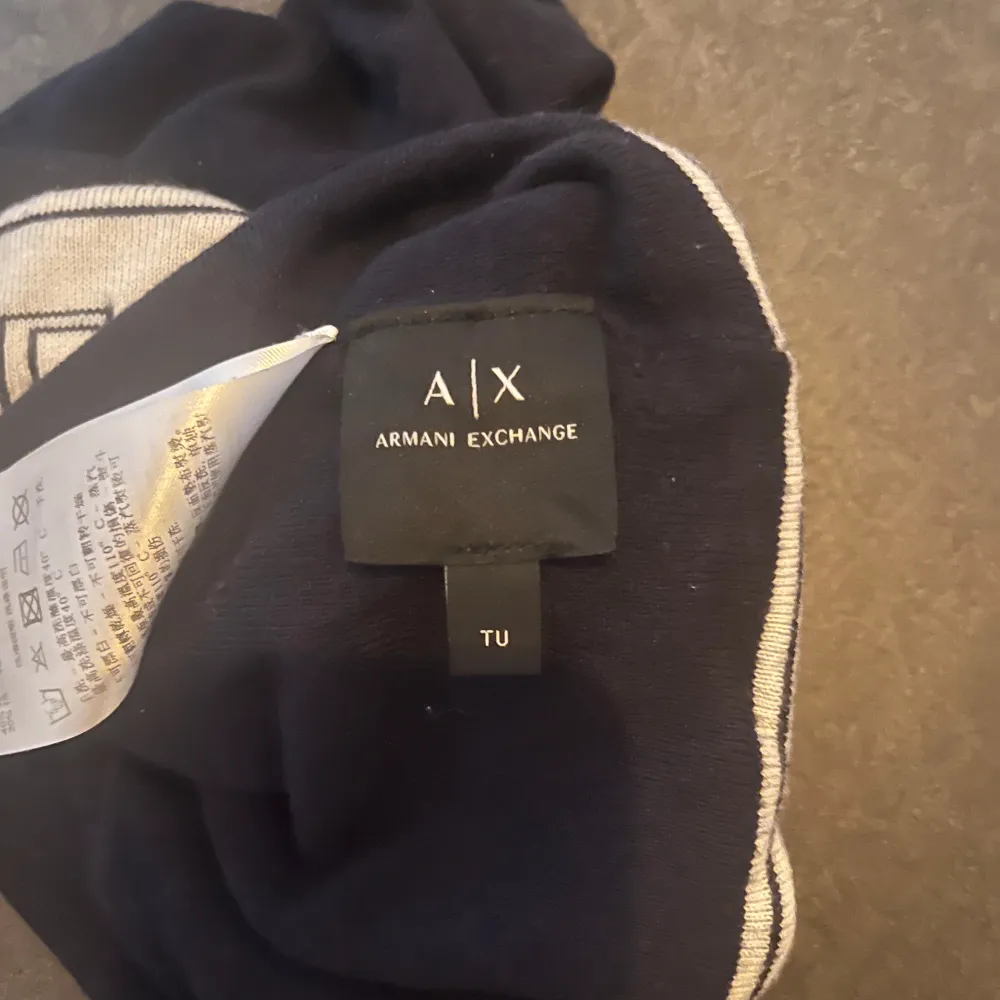 Snygg svart marinblå mössa från Armani Exchange med vit kant och logotyp. Perfekt för att hålla värmen med stil. Tillverkad i mjukt material för en bekväm passform.. Asusteet.