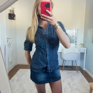 Jeanstopp - Snygg jeanstopp i mörkare denim med knappar framtill och trekvartsärmar. Toppen har en figurnära passform och en bröstficka. Perfekt för fest/middag💕 Storlek 36 från Lindex🌸