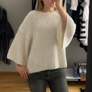 Vit stickad tröja med vida ärmar - Säljer en mysig vit stickad tröja med vida ärmar. Perfekt för kyliga dagar och ger en avslappnad look. Tröjan har en rund hals och en lös passform som gör den bekväm att bära. Passar både xs-s, jag är 157cm