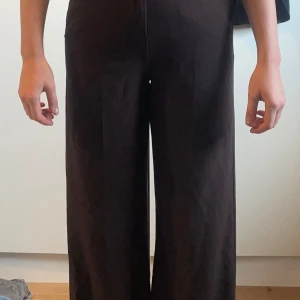 Bruna byxor från b.young - Snygga bruna byxor från b.young med hög midja och en elegant wide fit. Perfekta för en stilren look. Byxorna har en slät design utan synliga detaljer och är tillverkade i ett mjukt material.