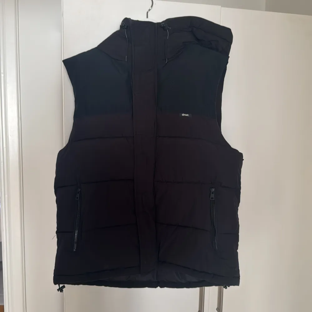 Säljer en svart dunväst från Zara med dragkedja och huva. Västen har en stilren design med två praktiska fickor framtill. Perfekt för kyligare dagar.. Takit.