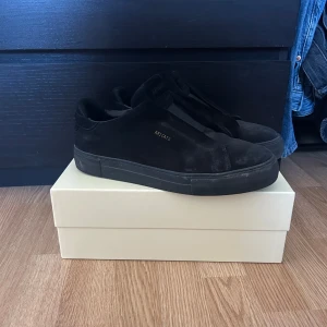 Svarta sneakers från Axel Arigato - Snygga svarta sneakers från Axel Arigato med en stilren design. Skorna har en rund tå och är tillverkade i mocka. Perfekta för en minimalistisk look. Gör rent skorna innan jag skicka iväg! Har knappt använd dom men har blivit smutsiga fort. Så fortfarande väldigt nyskick!