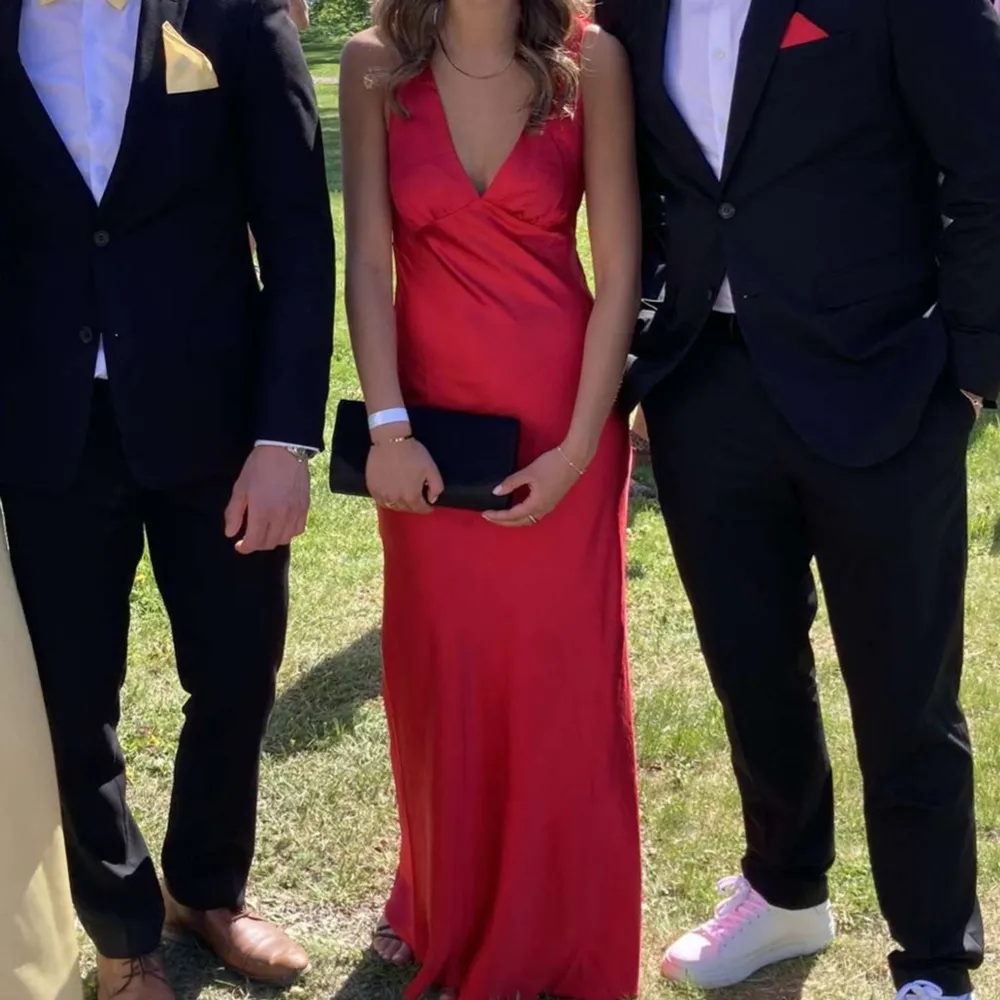 Elegant röd balklänning i satin med djup v-ringning och öppen rygg. Köpt för 1500kr och endast använd en gång. Storlek XXS men passar även XS och S. Köpt från Showpoo.. Mekot.