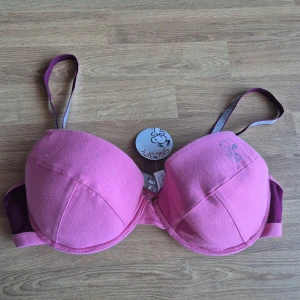 Rosa BH med Snoopy-motiv 85B - Säljer en söt rosa BH med ett tryck av Snoopy på ena kupan. BH:n har justerbara axelband och en bekväm passform. Perfekt för dig som älskar Peanuts-karaktärer! 💖. Storlek 85B. Är helt ny, kommer från konkurslager och har orginallappen kvar. För dyr? Kom med prisförslag.
