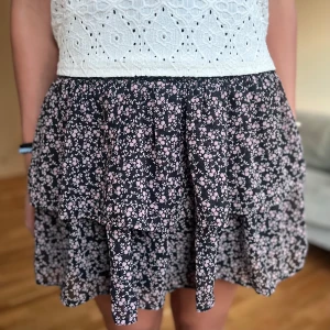 Blommig kjol från Kappahl - Säljer en söt blommig kjol från Kappahl i svart och rosa. Midjan är lite högre men går att få lågmidjad genom att vika ner kanten, det ser både naturligt och snyggt ut!😊 Säljer då den inte kommer till användning😅