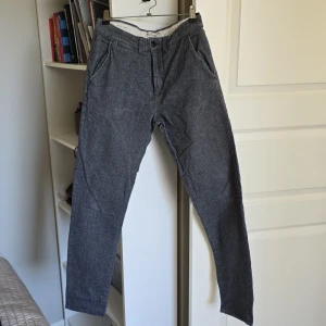 Grå kostymbyxor - Snygga grå kostymbyxor med en klassisk straight passform. Byxorna har diskreta fickor fram och bak samt en knappstängning i midjan. Perfekta för en stilren look.