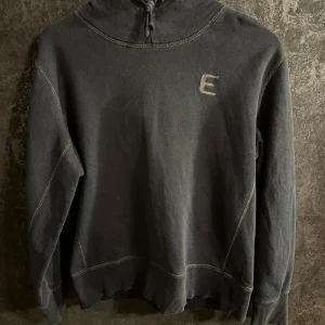 Mörkblå hoodie med broderad logga - Säljer en stilren mörkblå hoodie med en broderad logga på bröstet. Tröjan har en bekväm passform med långa ärmar och en praktisk huva. Perfekt för kyliga dagar!