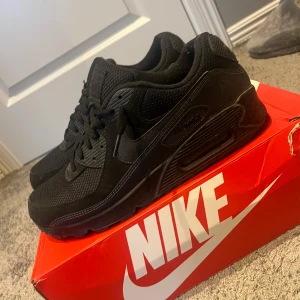Nike Air Max 90  - Snygga helsvarta Nike Air Max 90s med klassisk design. Skorna har en bekväm passform och är utrustade med den ikoniska Air Max-dämpningen. Perfekta för både stil och komfort. Inga defekter , lite smutsiga men med en snabb tvättning blir det som ett par helt nya skor. Köpt i december 2024 och ej använt mycket. Pris kan diskuteras vid snabb affär. Nypris 1850